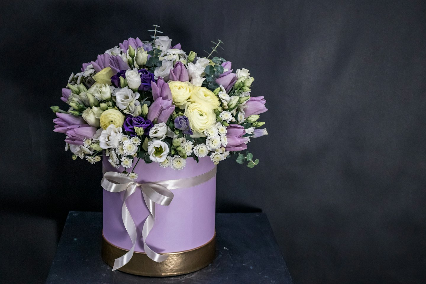 En blomsterbukett i en lavendellåda med ett band.